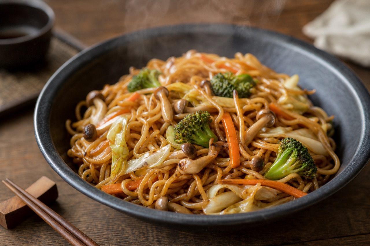 Yakisoba de shimeji com brócolis, cenoura e repolho em bowl escuro com hashi